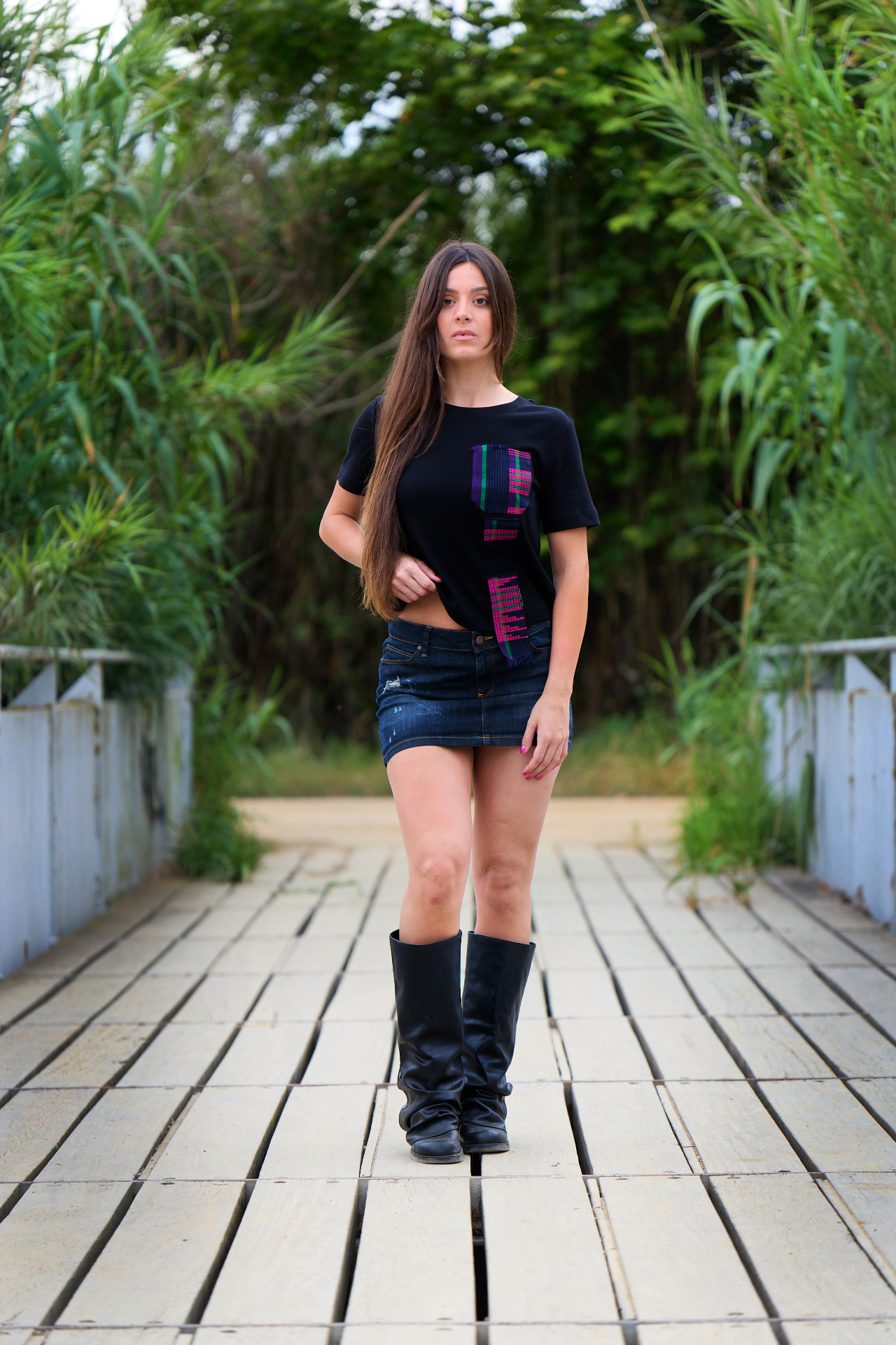 Front view of the black Asooke Urban Tee worn with a denim skirt